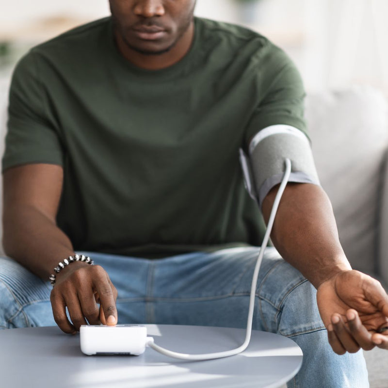 Man measuring blood pressure with digital arm cuff monitor at home