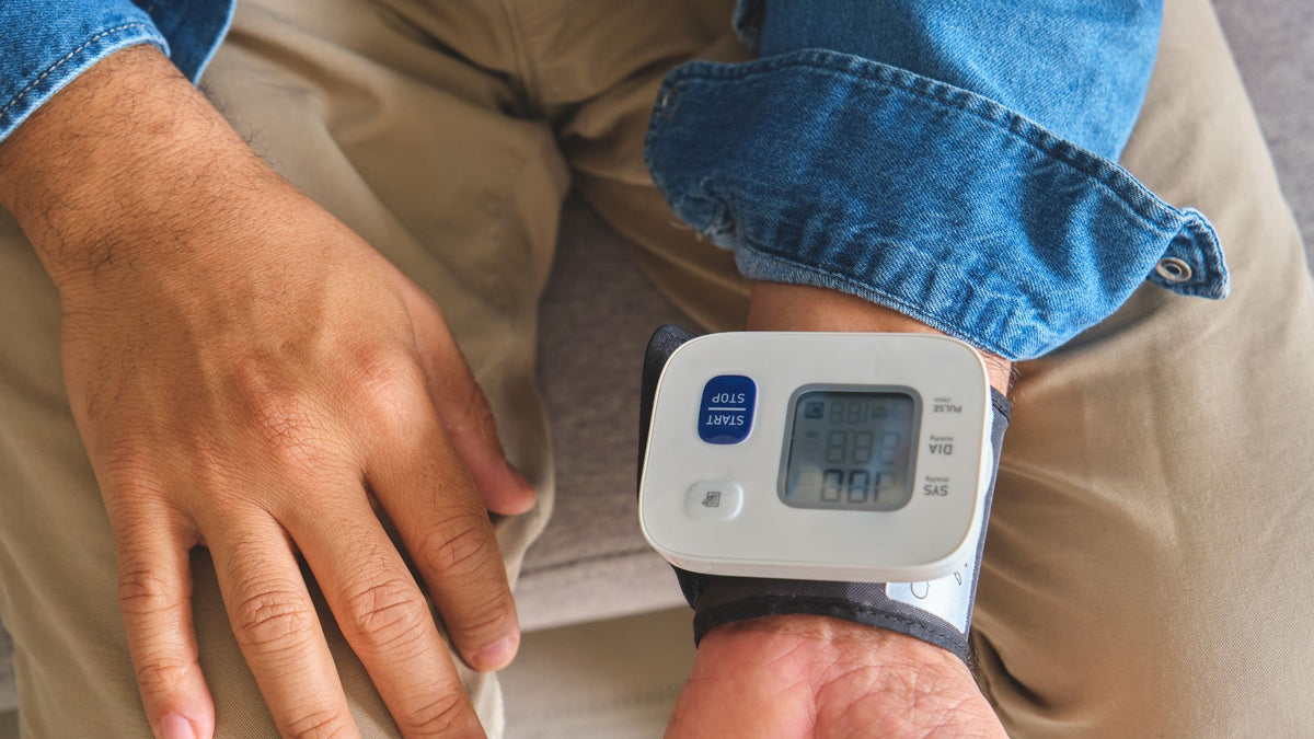 Close-up of digital wrist blood pressure monitor displaying health reading on wrist